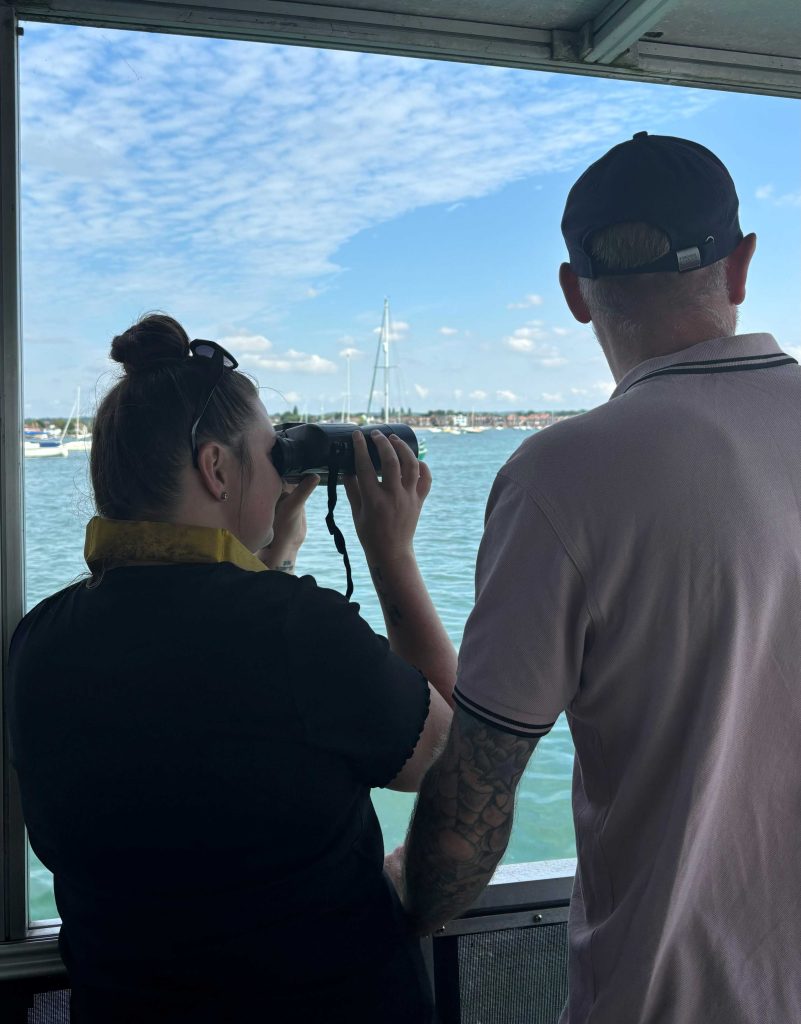 Couple looking out of binoculars on Chichester harbour boat trip 